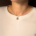 Liminoko Nugget-Anhänger aus recyceltem Gold, handgefertigt, getragen zu schlichtem weißen Shirt im warmen Licht.