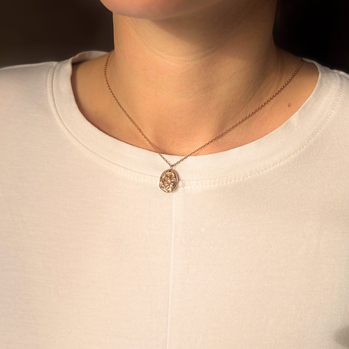 Liminoko Nugget-Anhänger aus recyceltem Gold, handgefertigt, getragen zu schlichtem weißen Shirt im warmen Licht.