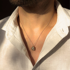 Liminoko Nugget-Anhänger aus recyceltem Gold in Weißgold mit Gelbgold Akzenten handgefertigt, getragen zu offenem weißen Hemd im warmen Licht.