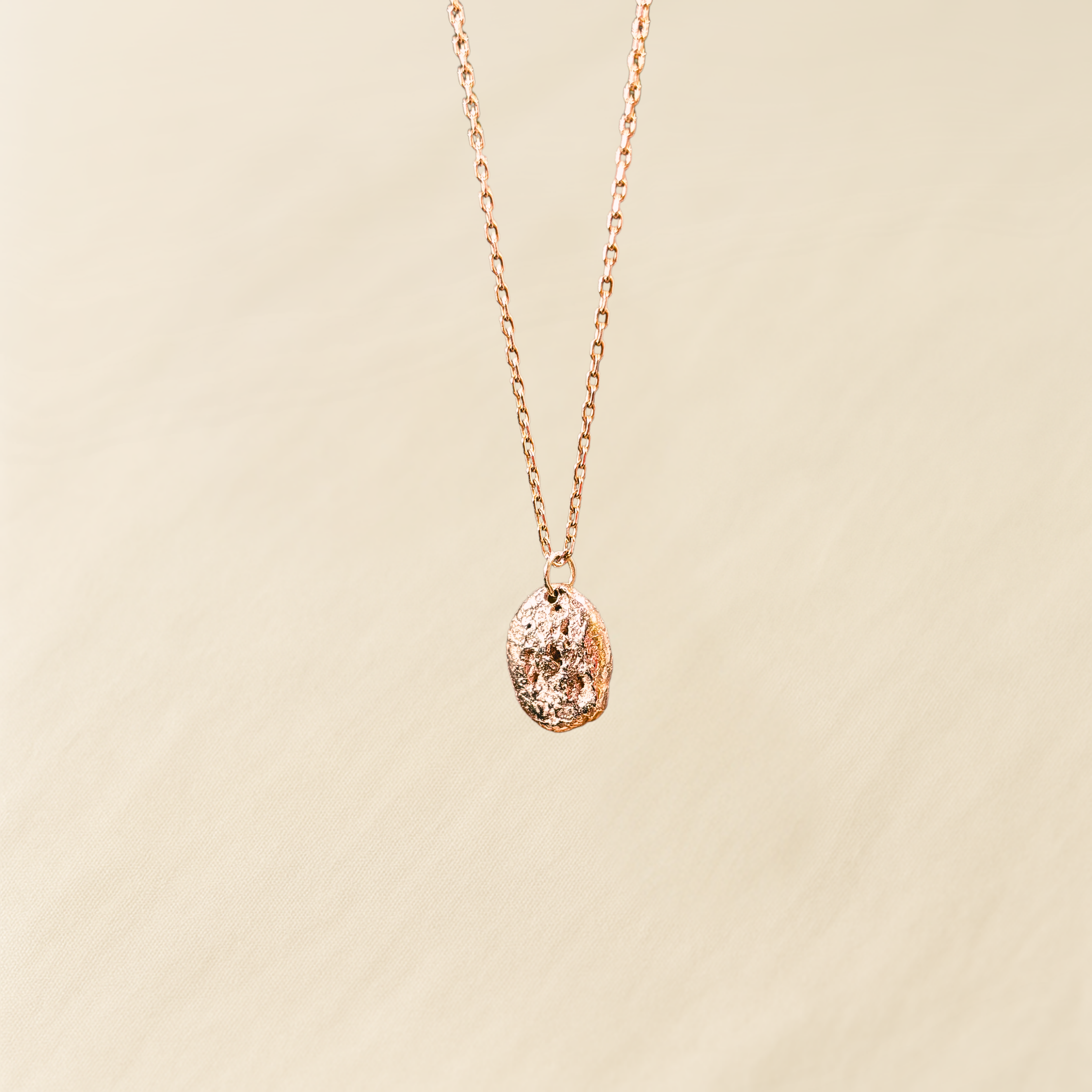 Re-Loved Liminoko Nugget-Anhänger aus Roségold an feiner Kette, luxuriös und einzigartig handgefertigt aus recyceltem Schmuck, vor hellem Stoffhintergrund.